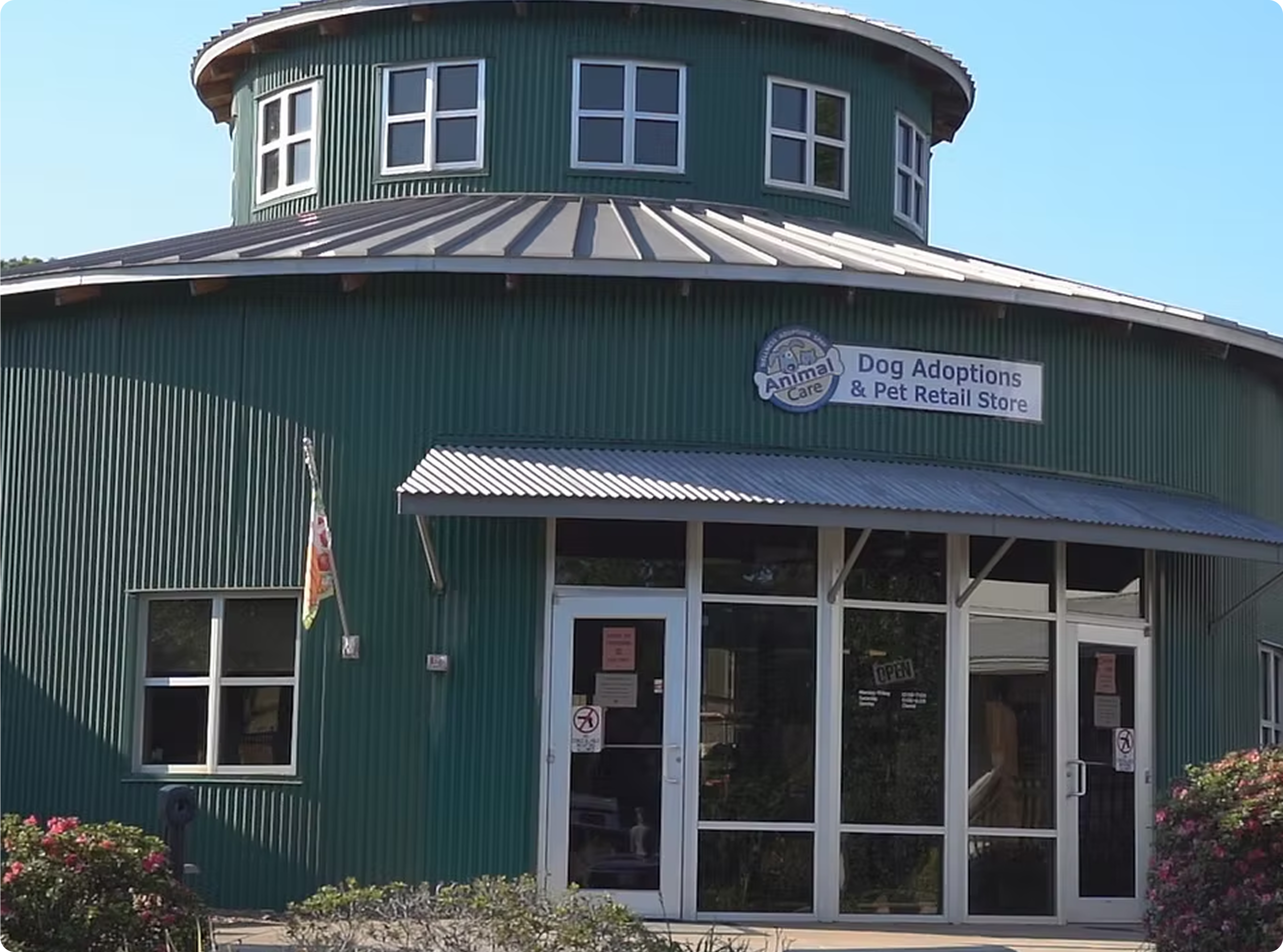 Green round building with 'Dog Adoptions & Pet Retail Store' sign on a clear day