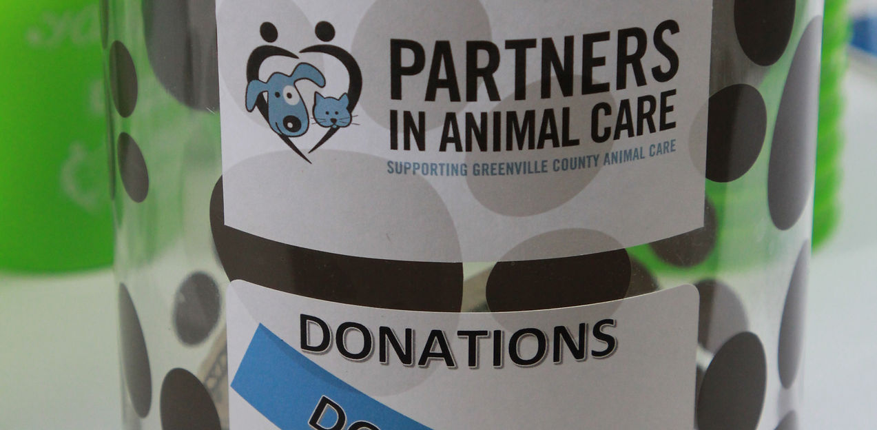 Polka dot container with 'Partners in Animal Care' label on a blurred background